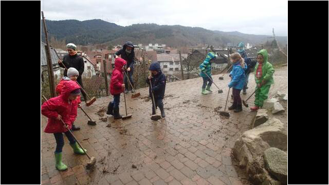 Kindergartenkinder beim Stall saubermachen